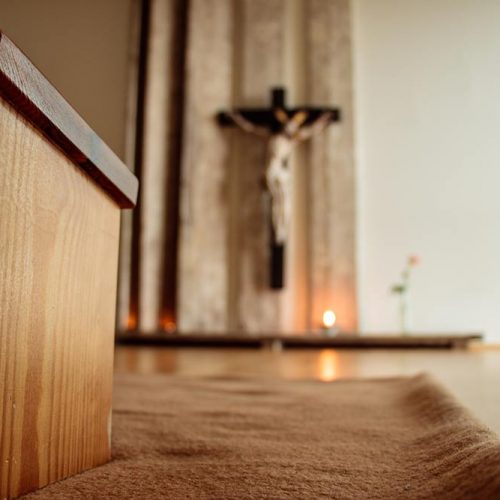 Gemütlicher Meditationsraum mit Gebetshocker, Kreuz und Kerzen